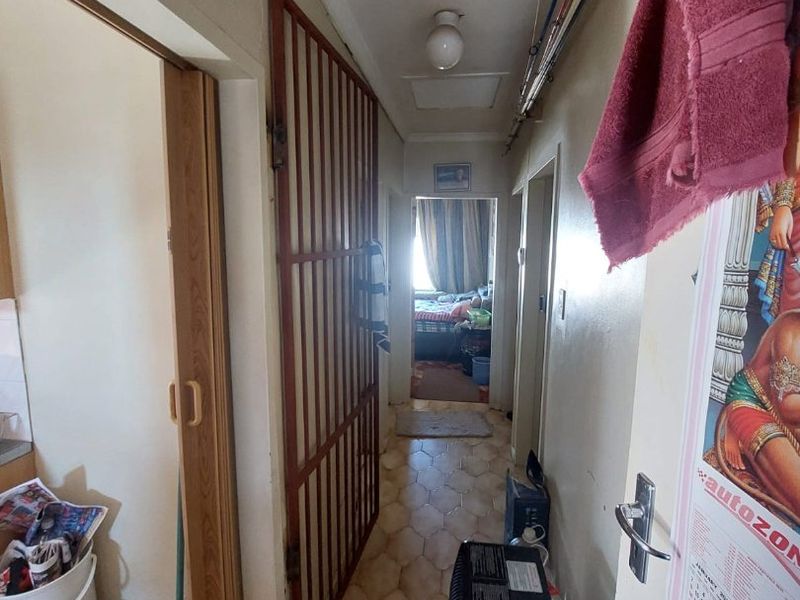 A functional hallway featuring vinyl flooring, a security gate, and access to a loft space, connecting various rooms within the home.