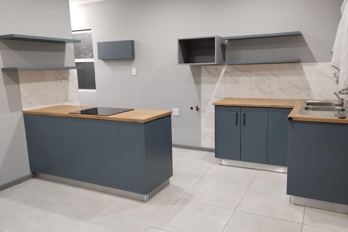 Modern kitchen featuring blue cabinetry, wooden countertops, an induction hob, double sink, and marble-look splashbacks in a clean, open-plan layout.