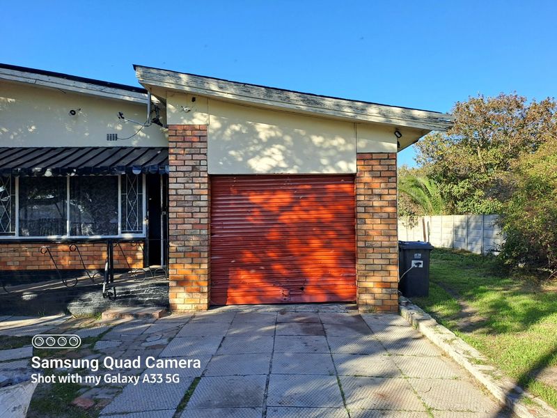 Exterior view of a residential property featuring a brick facade and a single roller shutter garage door with a paved driveway.