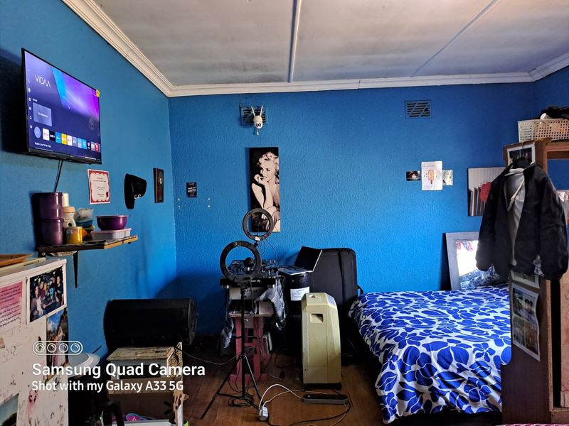 A bedroom featuring blue walls and a ceiling with visible staining and paint deterioration, requiring cosmetic updates to improve the overall condition.