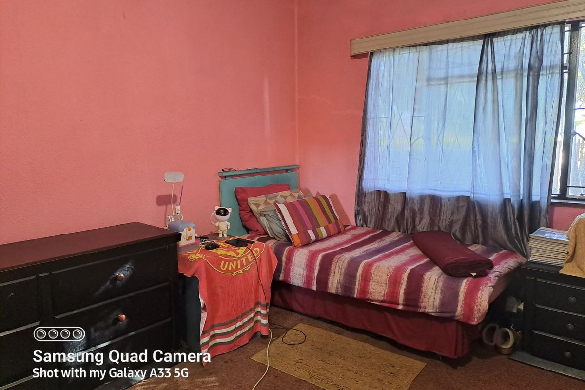 A bedroom featuring pink walls and a window with a curtain rail.