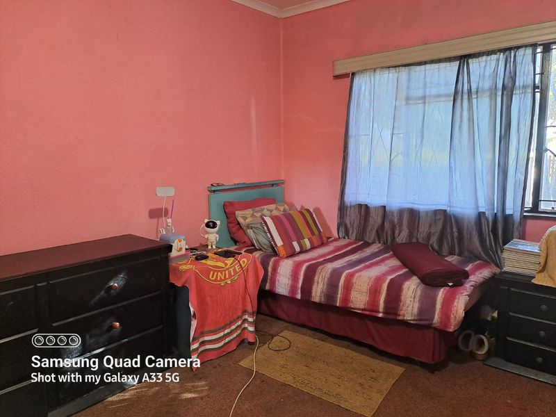 A bedroom featuring pink walls and a window with a curtain rail.