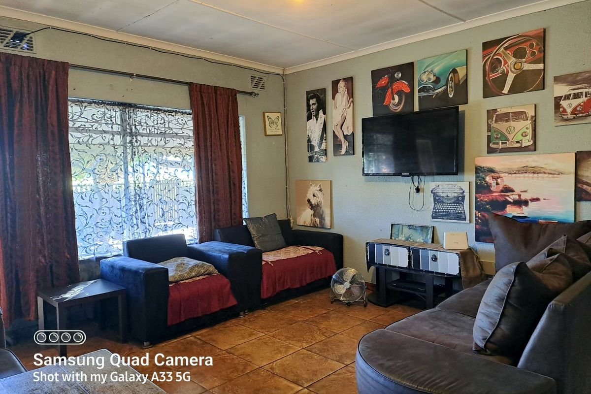A living room featuring tiled flooring and ceiling ventilation, currently styled with personal decor and wall-mounted television.