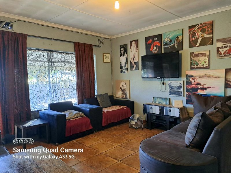 A living room featuring tiled flooring and ceiling ventilation, currently styled with personal decor and wall-mounted television.