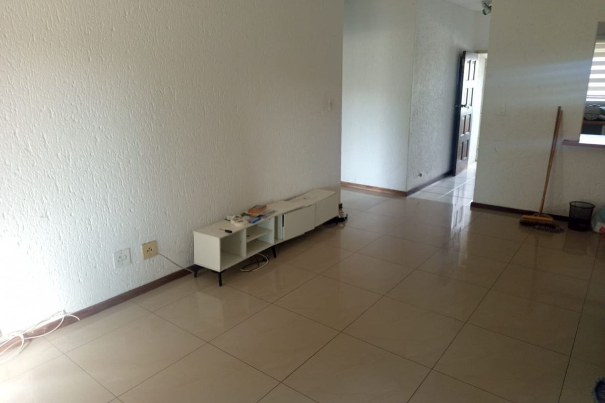 A spacious, empty living area featuring neutral tiled flooring and textured walls, providing a blank canvas for interior design.