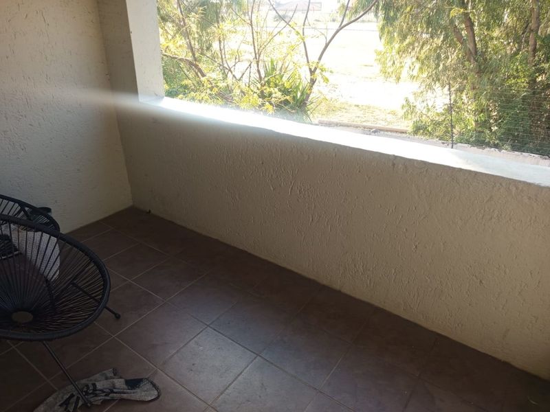 A covered balcony featuring tiled flooring and a solid masonry balustrade with security wire fencing, offering an outdoor space for relaxation.