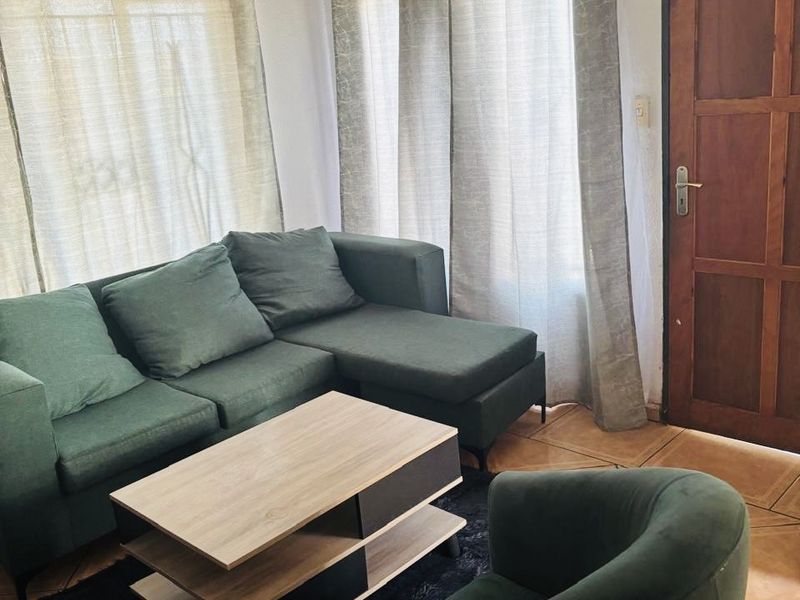 A living room area featuring tiled flooring and a traditional timber door, providing a functional space with potential for cosmetic updates.