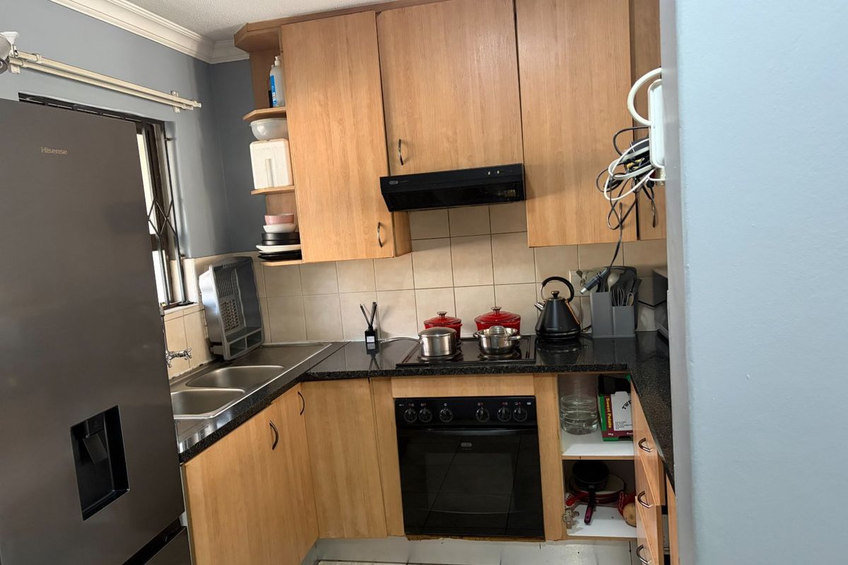 A functional kitchen featuring laminate cabinetry, granite countertops, a built-in oven with hob, and a double stainless steel sink with tiled backsplash.