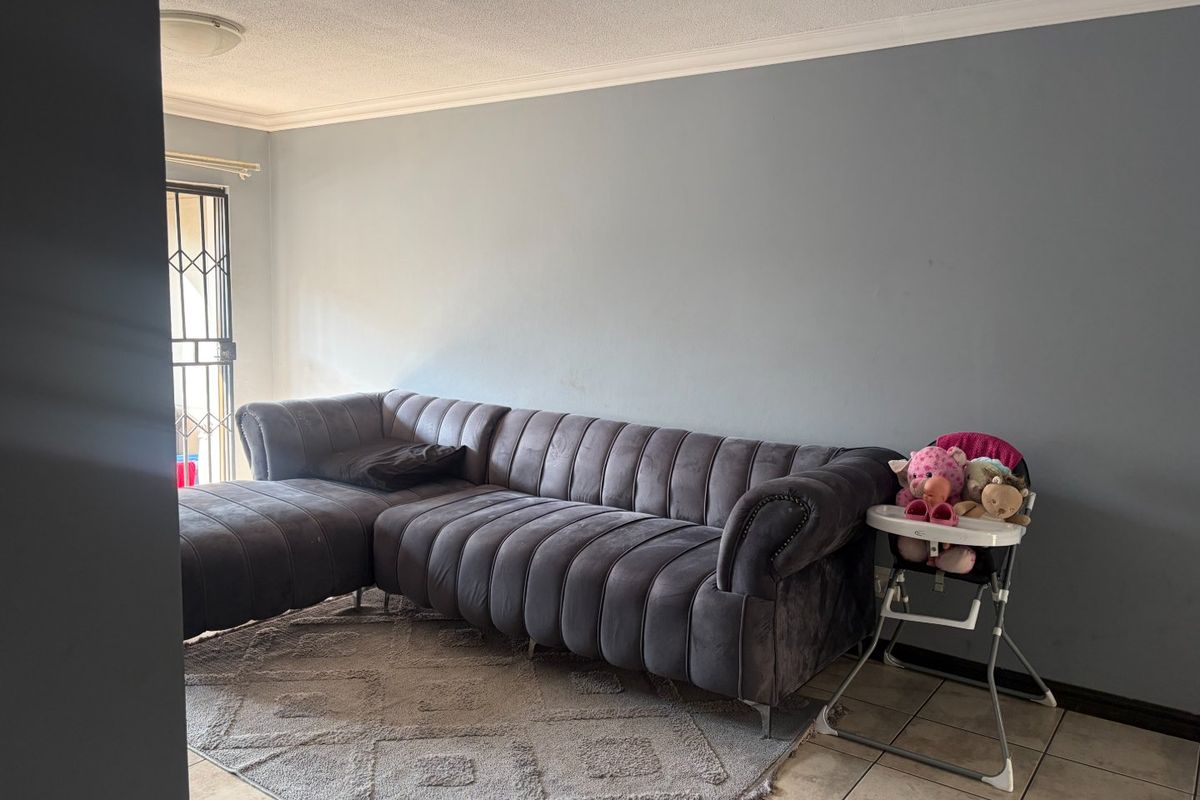 A living room area featuring tiled flooring, a security gate at the entrance, and neutral wall finishes.