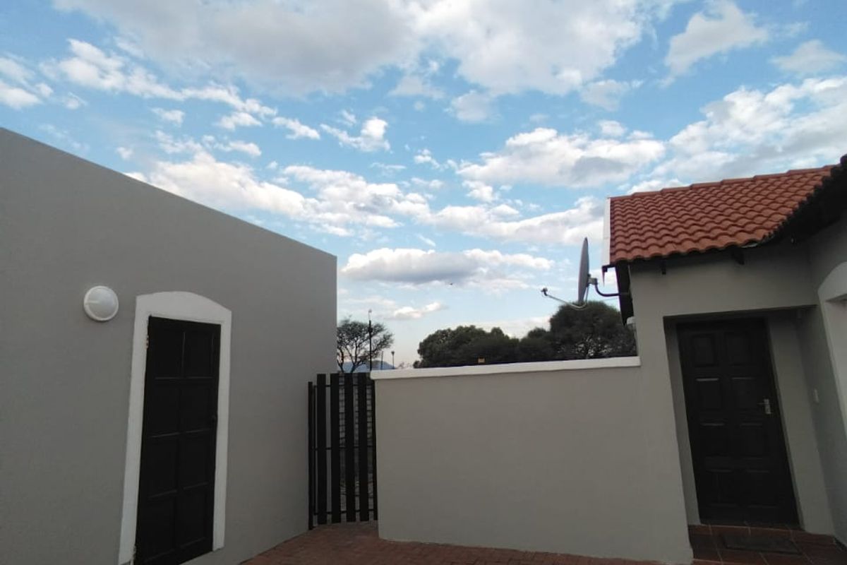 A well-maintained rear courtyard featuring brick paving, boundary walls, and access to the main dwelling and secondary structure.