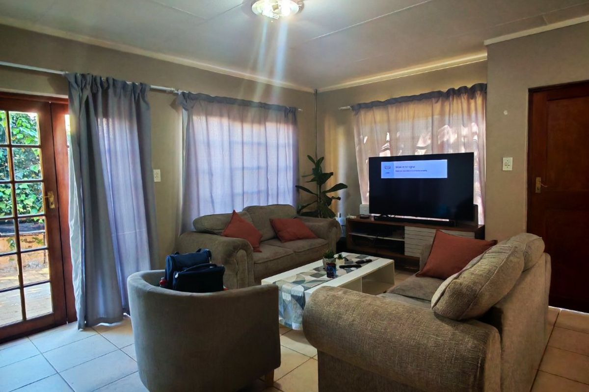 A living room featuring tiled flooring, a glass panel door leading to the exterior, and standard ceiling lighting.