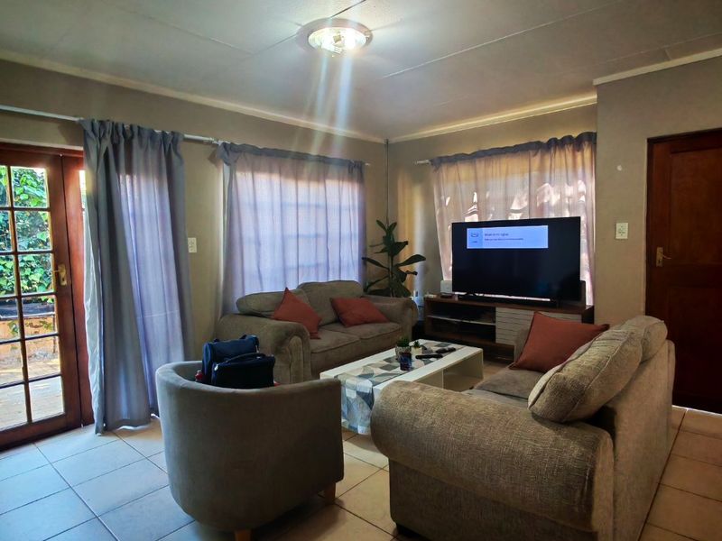 A living room featuring tiled flooring, a glass panel door leading to the exterior, and standard ceiling lighting.