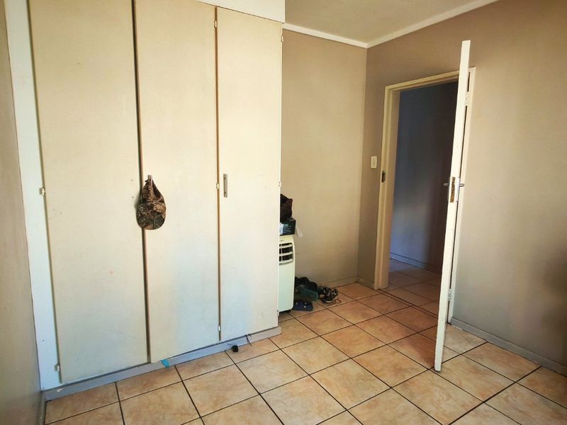 A bedroom featuring built-in cupboards and tiled flooring, offering a blank canvas for potential updates and interior design improvements.