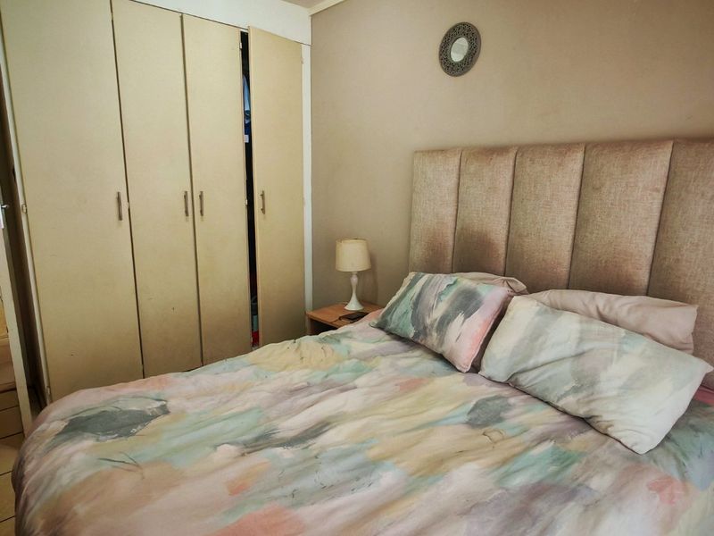 A bedroom featuring neutral wall tones and a built-in wardrobe with multiple doors.