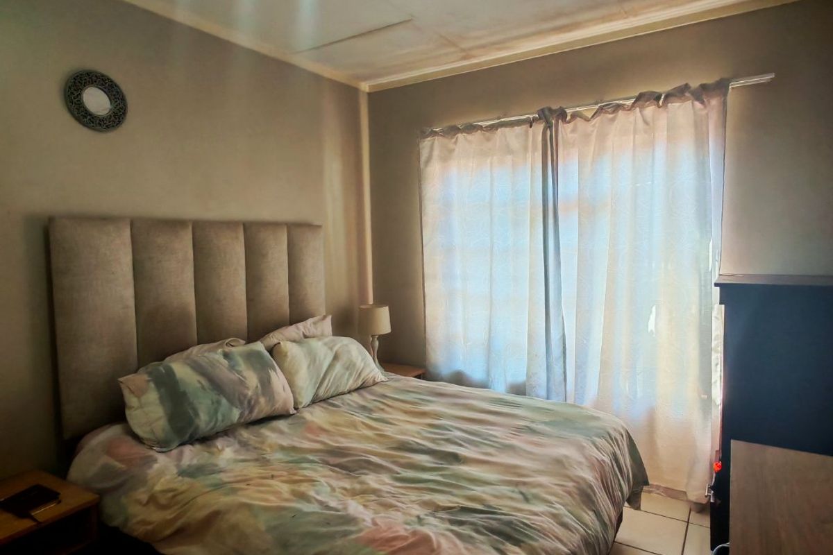A bedroom featuring tiled flooring and a ceiling showing signs of water damage and deterioration.