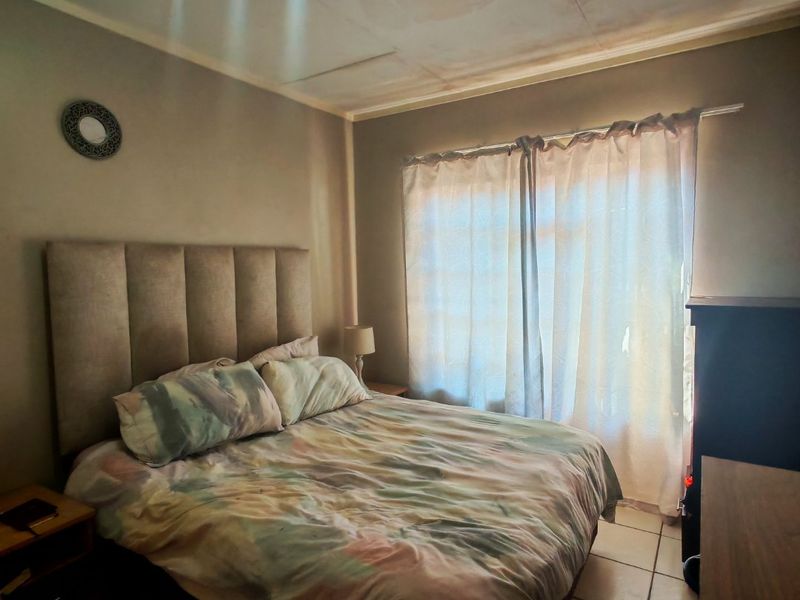 A bedroom featuring tiled flooring and a ceiling showing signs of water damage and deterioration.