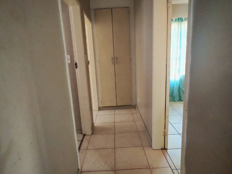 A functional hallway featuring tiled flooring and a built-in storage cupboard, providing access to adjacent rooms.