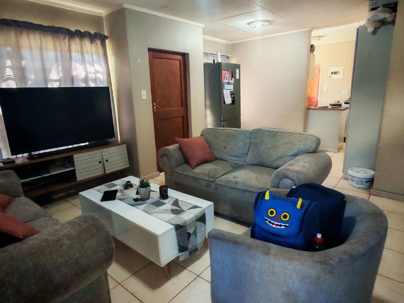 Open plan living area featuring tiled flooring and a connected kitchen space with breakfast counter.