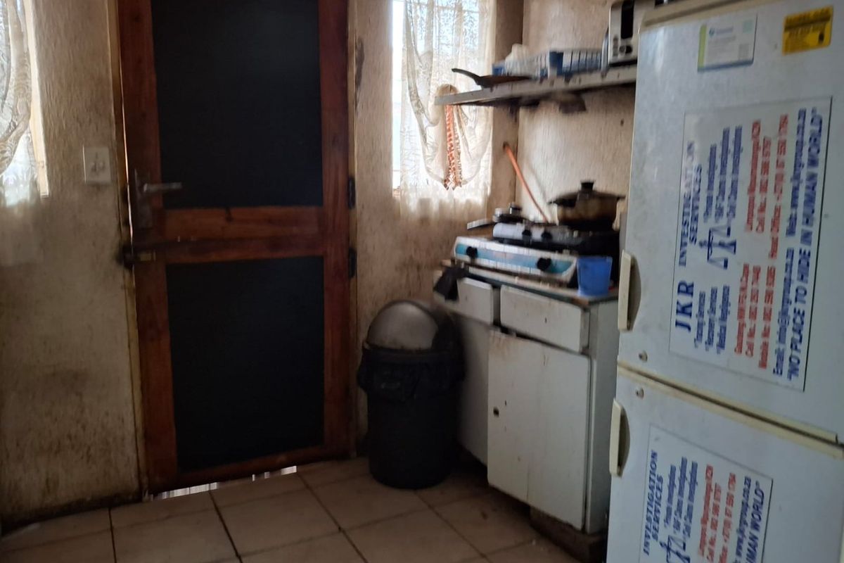 A compact kitchen area featuring tiled flooring, basic cabinetry, and a gas hob, requiring significant cosmetic updates and maintenance to improve its condition.