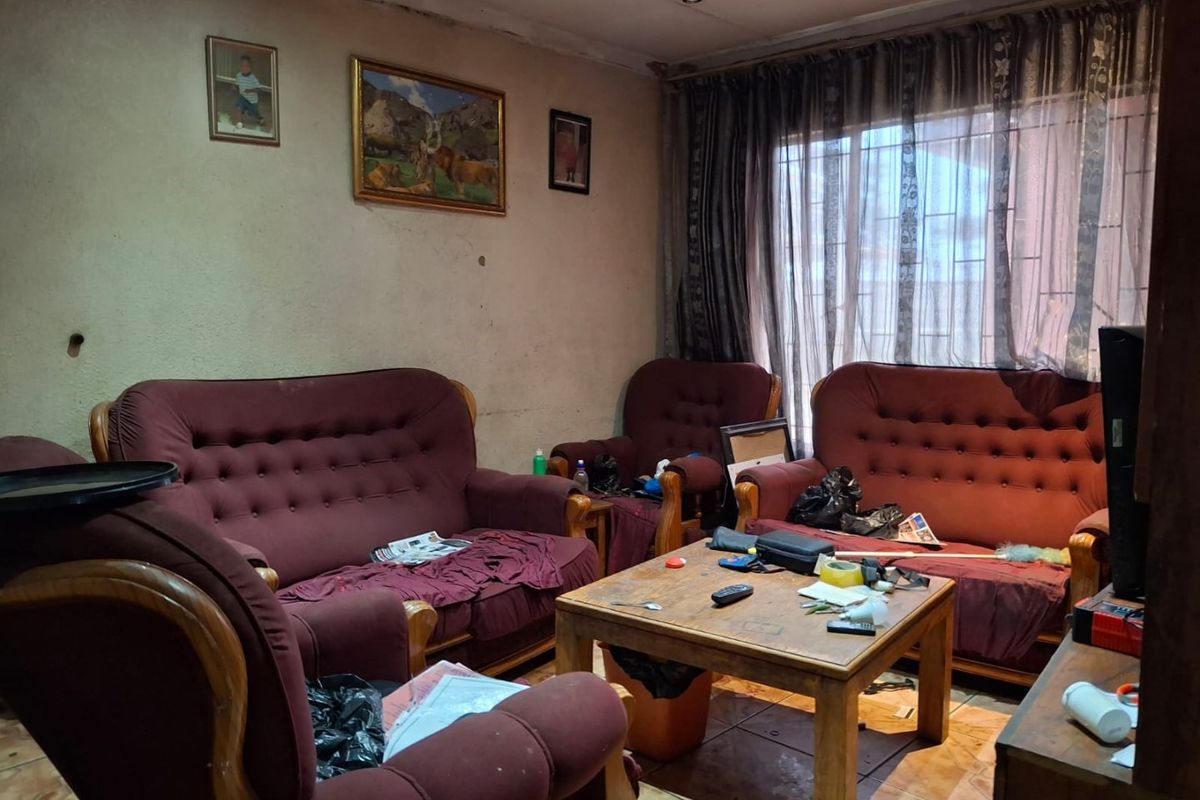 A living room featuring tiled flooring and recessed lighting, currently requiring cosmetic updates to the walls and ceiling to improve its overall condition.