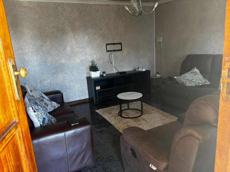 A living room featuring dark tiled flooring and a wall-mounted television bracket, offering a functional space with potential for modern updates.