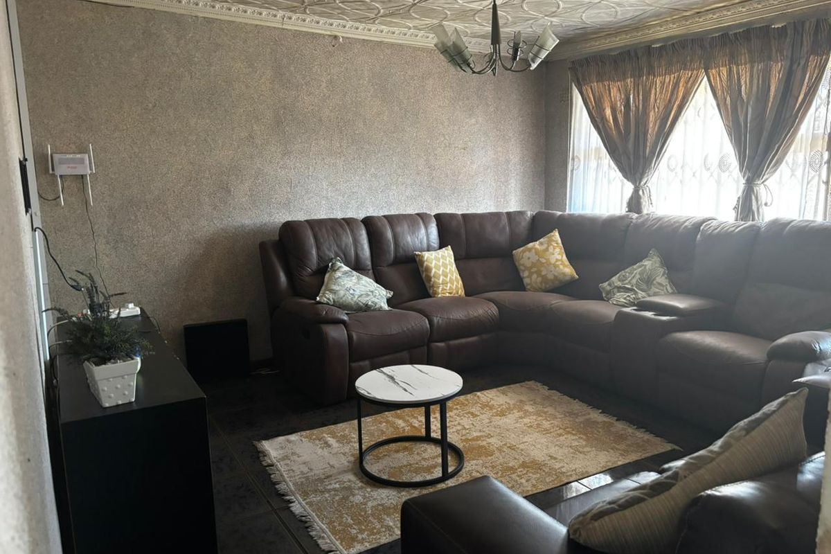 A living room featuring decorative ceiling tiles, coving, and tiled flooring, offering a dated aesthetic that could benefit from modern updates.