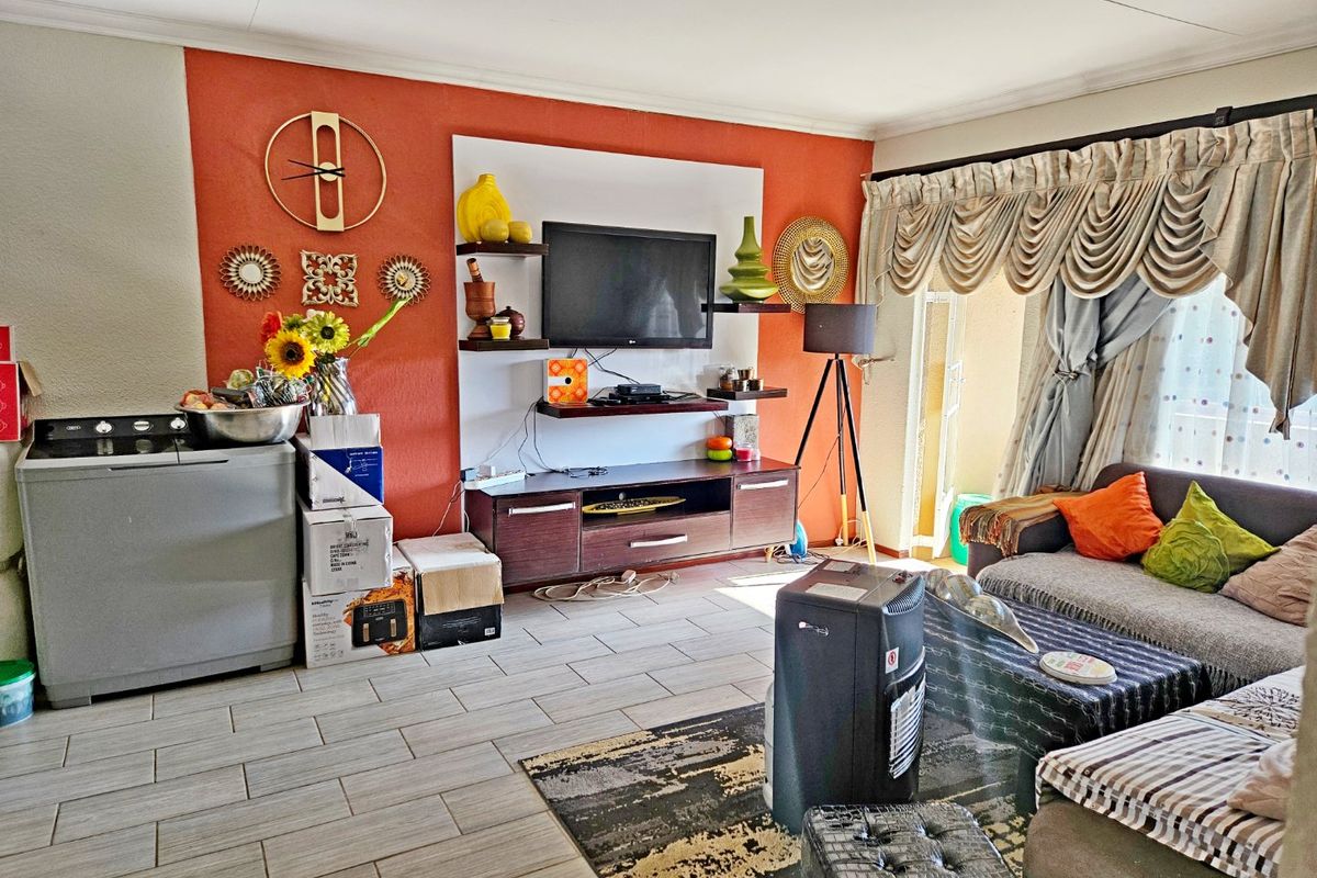 A living room featuring tiled flooring and a built-in media unit, with direct access to an outdoor area through a sliding door.