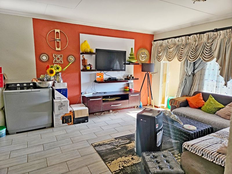 A living room featuring tiled flooring and a built-in media unit, with direct access to an outdoor area through a sliding door.