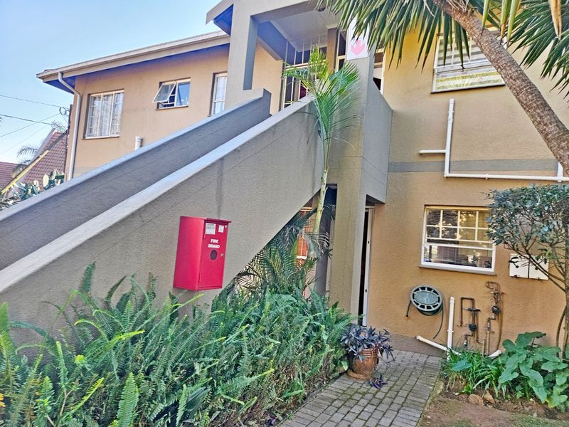 Exterior view of a townhouse complex featuring a concrete staircase, paved walkway, and visible fire safety equipment.