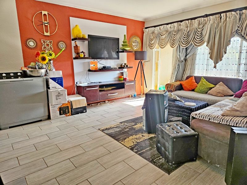 A living room featuring tiled flooring, a built-in media console, and a sliding glass door providing access to the exterior.