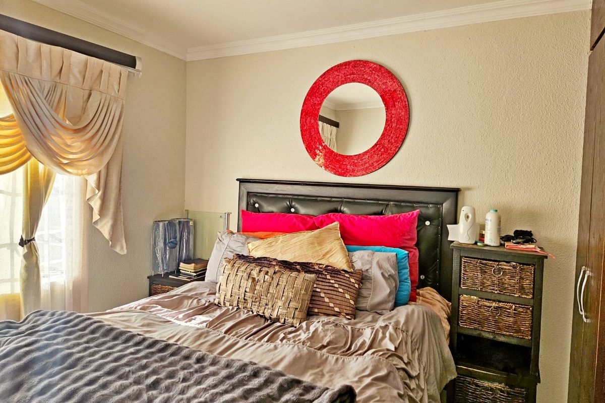 A cozy bedroom featuring a built-in wardrobe, decorative cornice detailing, and natural light from the side window.
