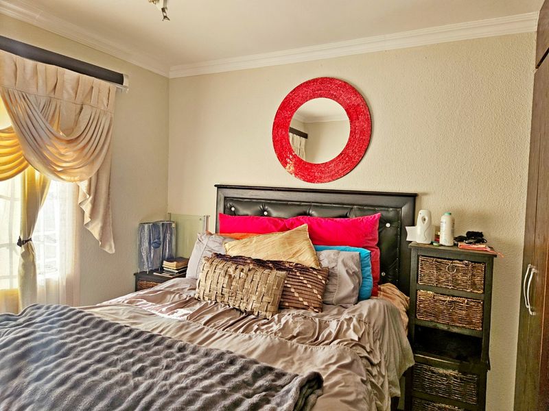A cozy bedroom featuring a built-in wardrobe, decorative cornice detailing, and natural light from the side window.
