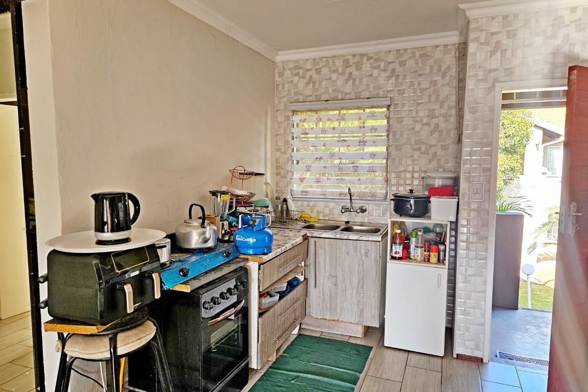 A compact kitchen area featuring a double basin sink, tiled backsplash, and built-in cabinetry, providing functional space for meal preparation.