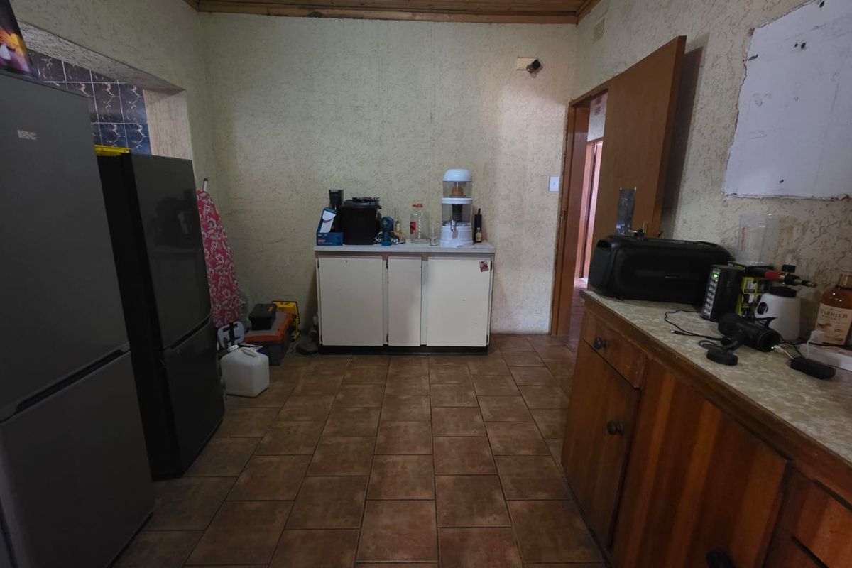 A functional kitchen space featuring tiled flooring, built-in cabinetry, and laminate countertops, offering potential for modernization and cosmetic updates.