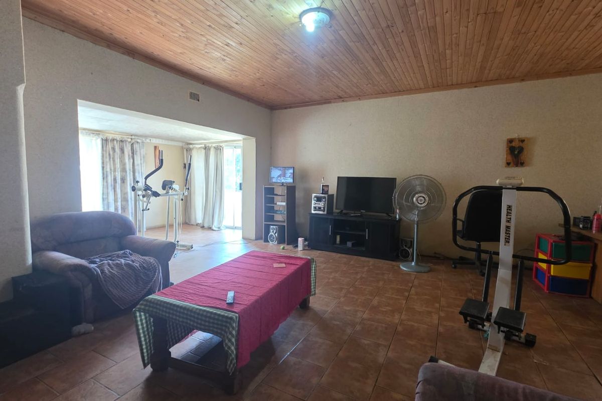 Spacious living area featuring ceramic floor tiles and a timber tongue and groove ceiling, with direct access to an adjoining sunroom or patio area.