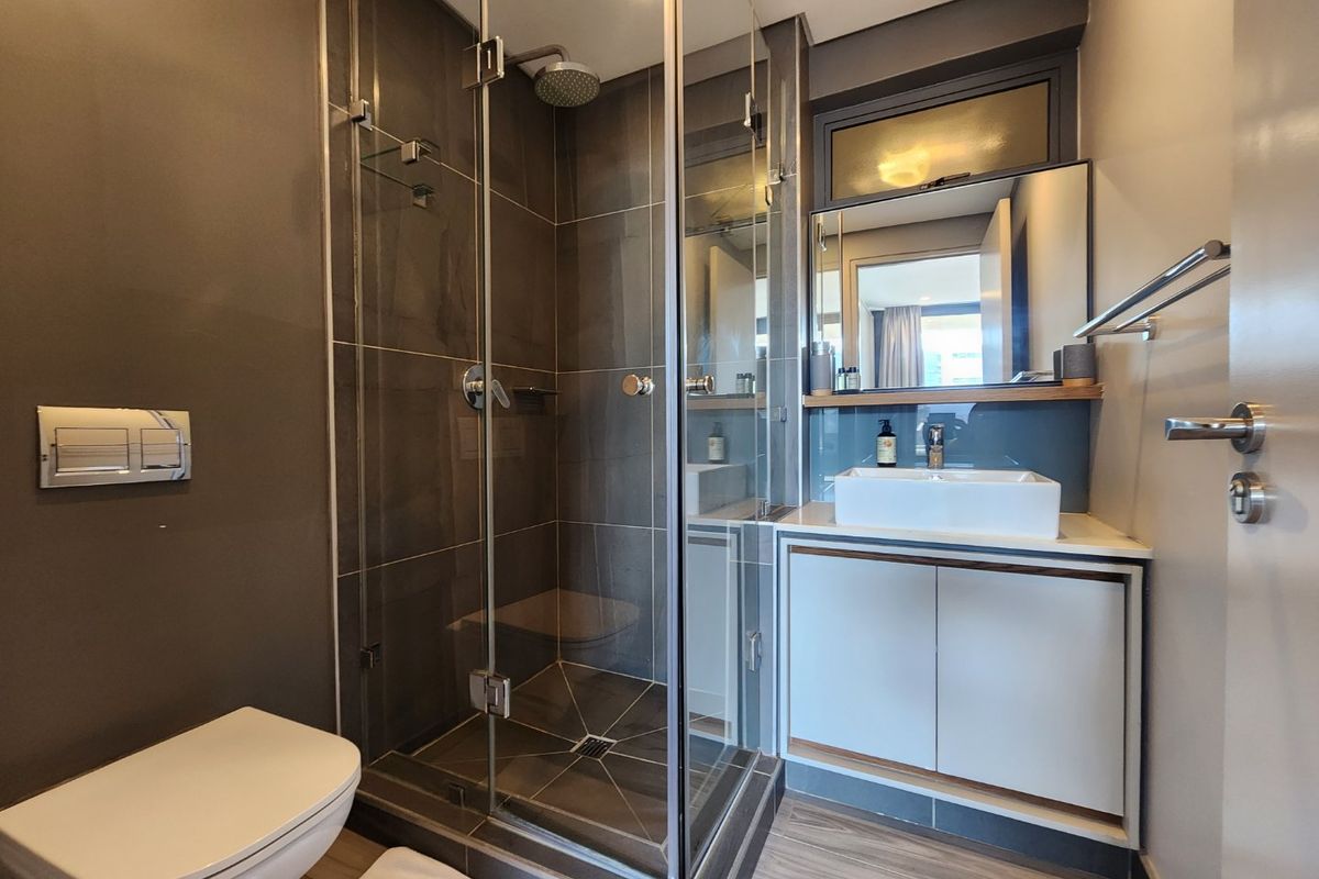 Modern bathroom featuring a glass-enclosed shower, wall-mounted toilet, and a sleek vanity with a vessel sink and contemporary finishes.