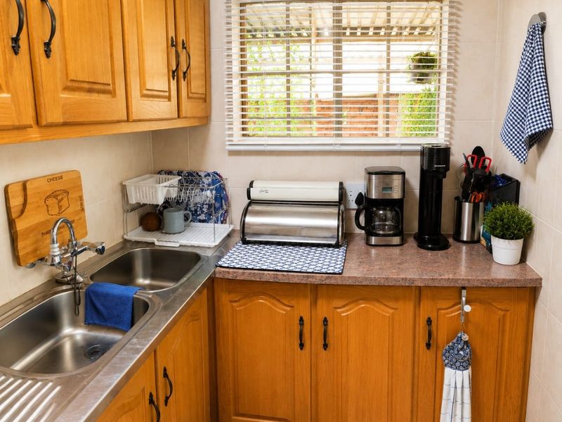 A functional kitchen area featuring timber cabinetry, a double stainless steel sink, and tiled splashbacks, providing a practical workspace with natural light.