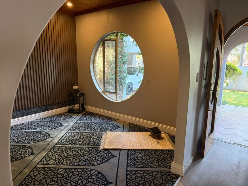 An inviting entrance hall featuring a distinctive circular window, arched architectural detailing, and elegant timber slat wall paneling.