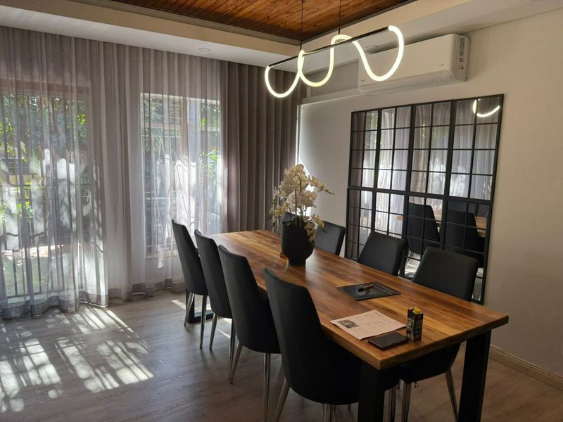 A well-appointed dining room featuring a timber-clad ceiling, modern pendant lighting, split-system air conditioning, and large glass doors providing ample natural light.