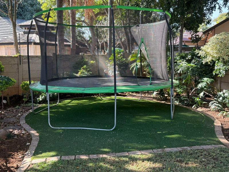 A landscaped garden area featuring artificial turf, neat brick edging, and a solid boundary wall.
