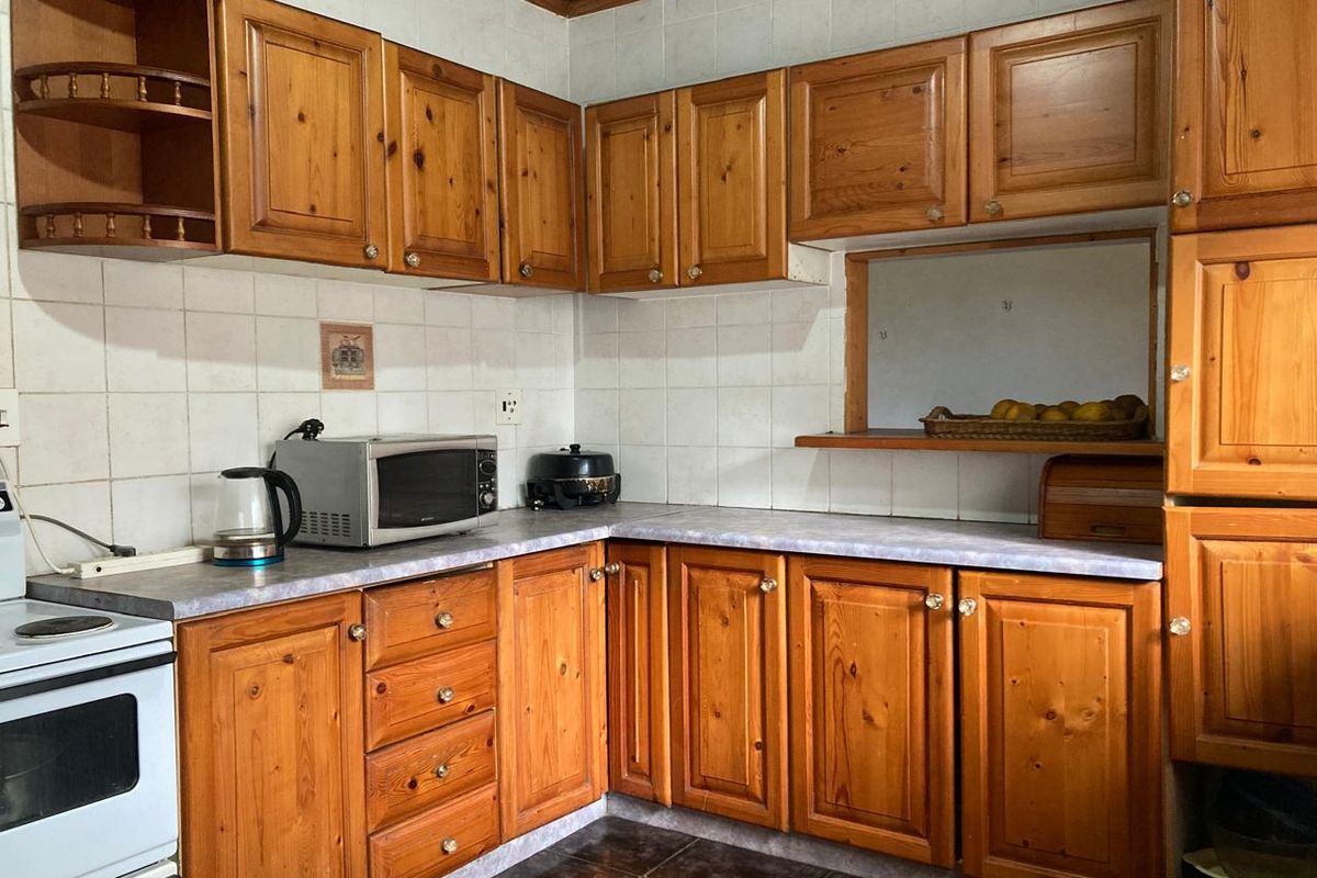 A functional kitchen featuring traditional timber cabinetry, laminate countertops, and a tiled splashback, offering a classic layout with potential for modern updates.
