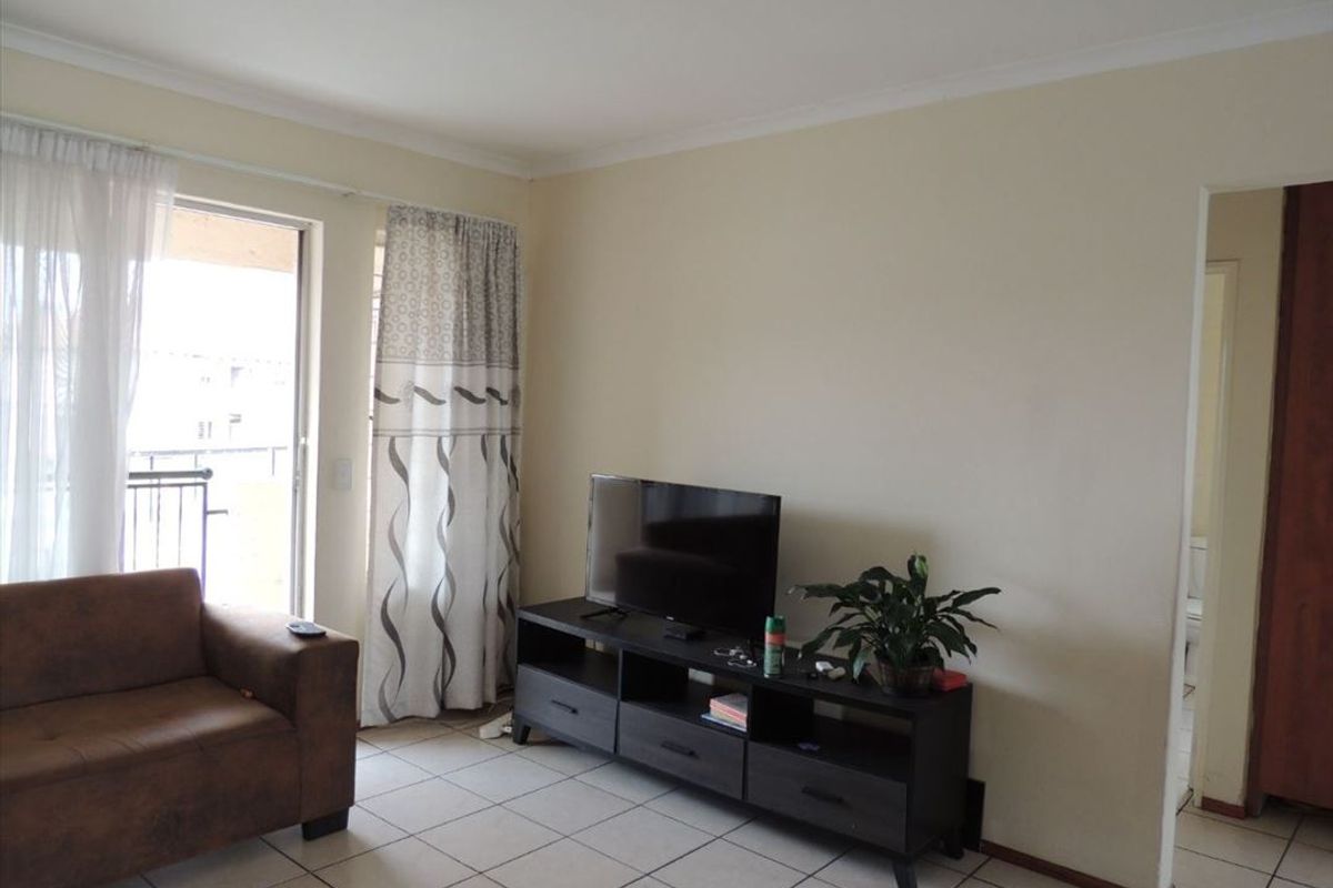 A living room featuring tiled flooring and a sliding glass door providing access to an outdoor area.