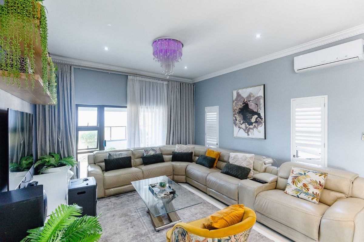 A well-maintained living room featuring crown molding, recessed lighting, a split-system air conditioner, and plantation shutters, with direct access to an outdoor area.
