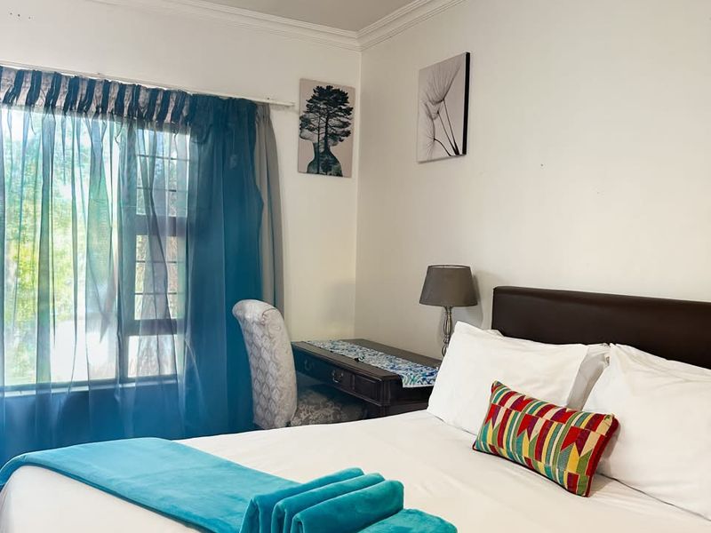 A well-lit bedroom featuring neutral walls, decorative cornice detailing, and a window fitted with security bars.