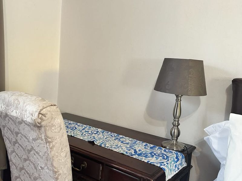A corner view of a bedroom featuring a small wooden desk and chair setup.