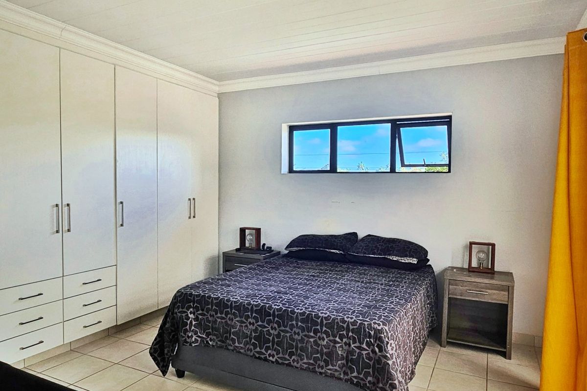 A well-maintained bedroom featuring built-in cupboards, tiled flooring, and a horizontal window providing natural light.
