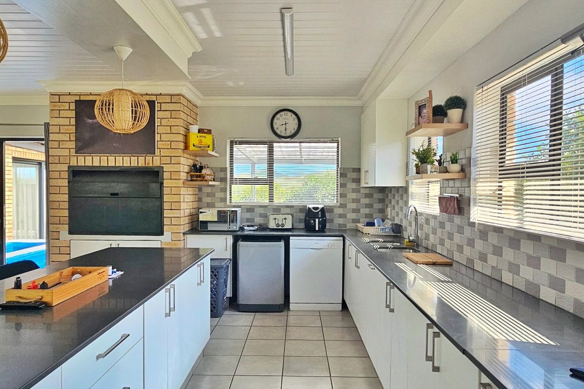 Modern kitchen featuring a central island, stone countertops, tiled backsplash, and a built-in fireplace, offering a functional and well-lit cooking space.