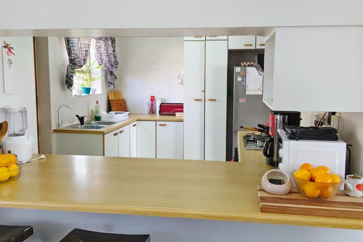 A functional kitchen featuring a breakfast bar, built-in cabinetry, and a tiled backsplash, viewed from the adjacent living area.