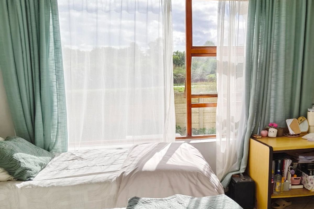 A bedroom featuring tiled flooring and a large timber-framed window that allows for natural light.