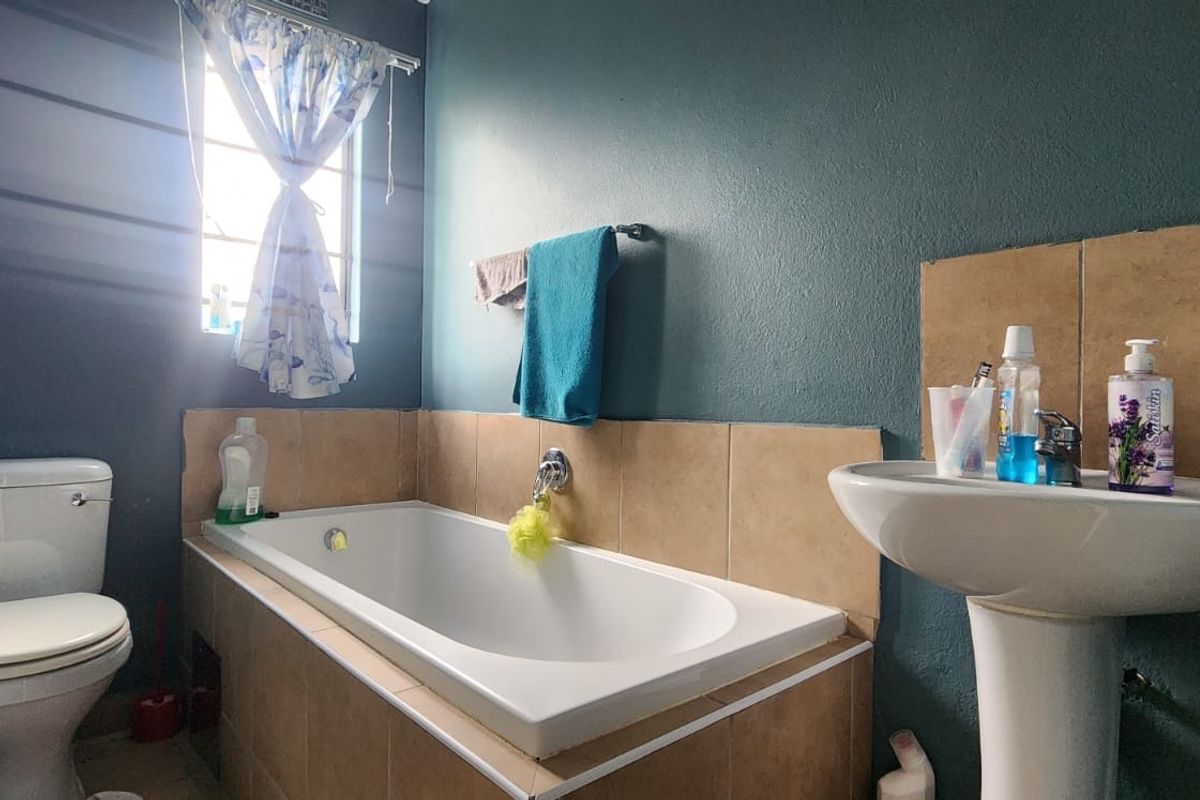 A functional bathroom featuring a pedestal basin, built-in bathtub, and toilet with dark painted walls and tiled splashback areas.